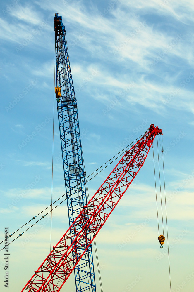 two construction cranes over blue sky two construction cranes over blue sky