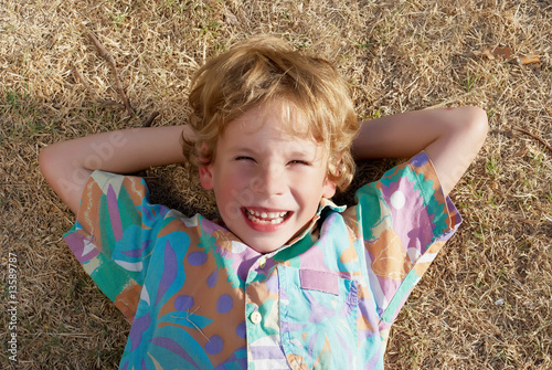 The little boy laying on a dry grass