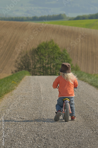 Kind mit Laufrad auf Feldweg