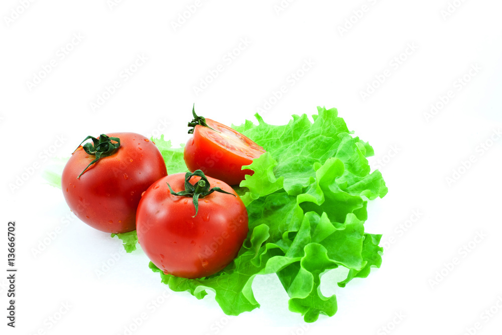 two and half red tomatos on leaves of lettuce two and half red tomatos on leaves of lettuce