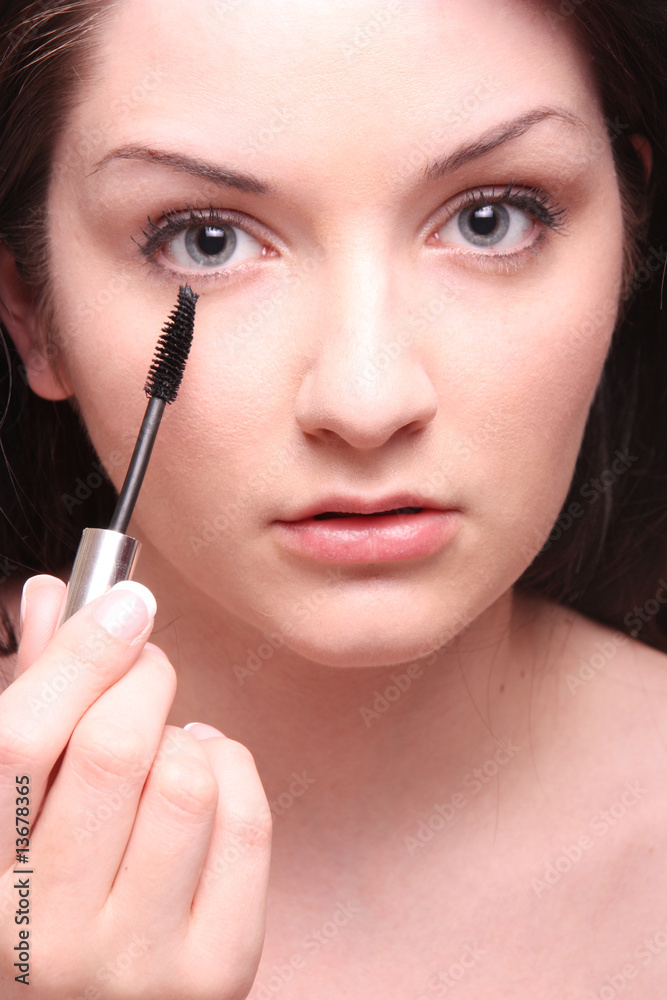 Beautiful brunette applying mascara/makeup