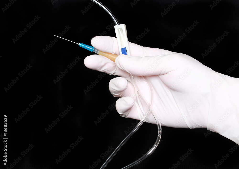 Hand in medical gloves, disposable infusion set with needle Stock Photo