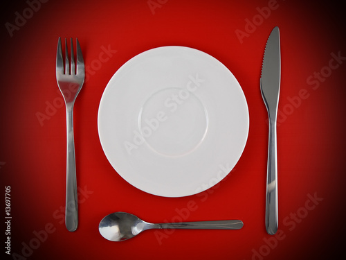 Fork, knife, spoon, plate on red background
