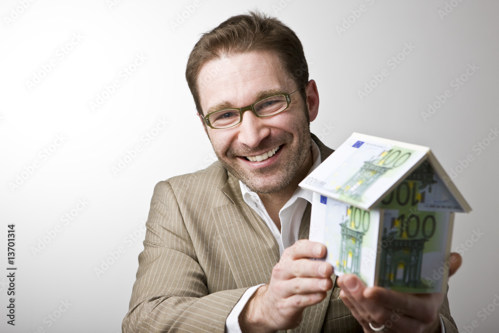 Junger Mann mit Haus aus Geldscheinen Junger Mann mit Haus aus Geldscheinen