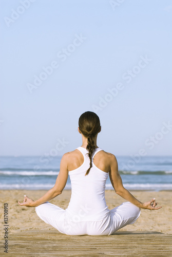 Frau im Lotussitz meditiert am Strand