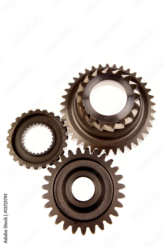 Three steel cogwheels meshing together over white Three steel cogwheels meshing together over white