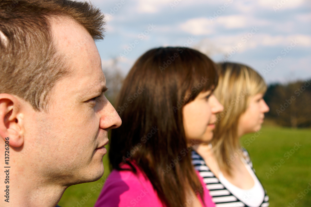 One male two woman profile view in a row smiling One male two woman profile view in a row smiling