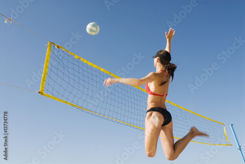 Junge Frau spielt Volleyball am Strand