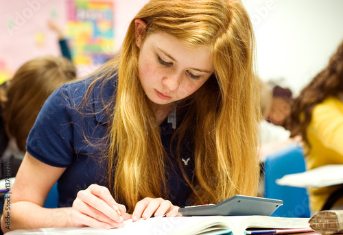 Strawberry blonde teenage girl doing math work