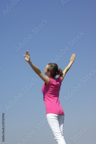 Sporty girl ready to fly on blue sky background © Alexey Pavluts