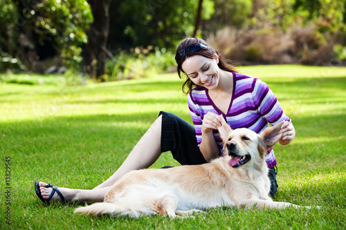Young woman pulling ears of golden retriever