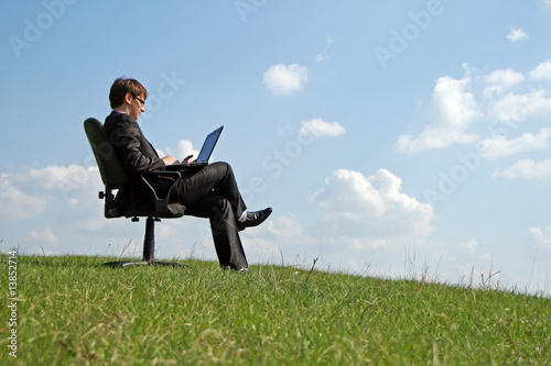 Businessman on office chair working with a laptop outdoor