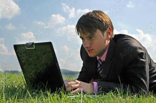 Businessman working with a laptop outdoor on grass © Lucian Tiut