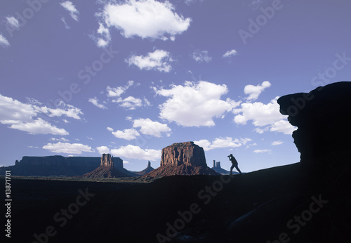 A silhouetted tourist photographing Monument Valley