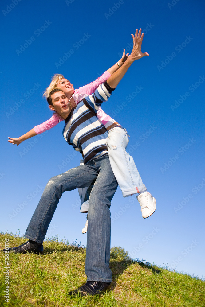 Happy young couple jumping in sky above a green meadow Happy young couple jumping in sky above a green meadow
