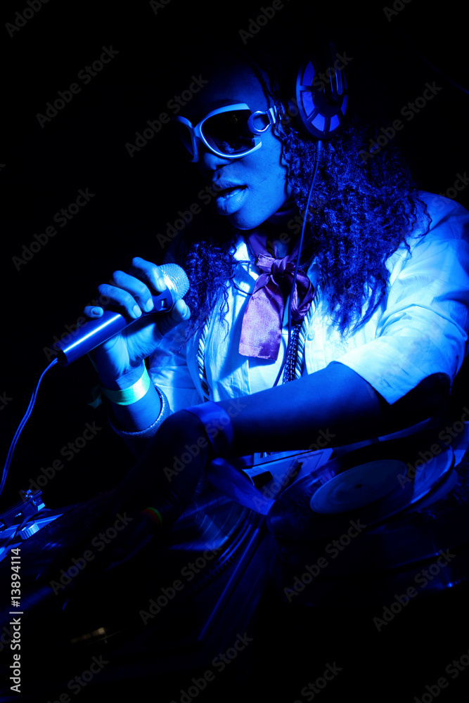 cool afro american DJ in action under blue light