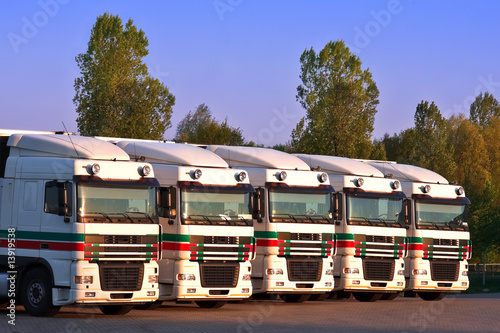 five trucks in a row with trees and blue sky in the background