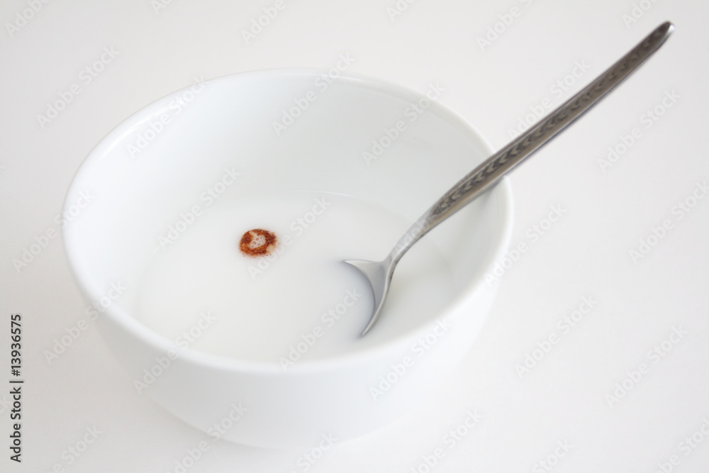 An bowl of milk with one peace of cereal floating in the milk. An bowl of milk with one peace of cereal floating in the milk.