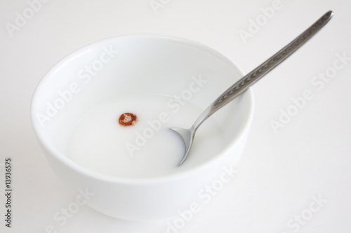 An bowl of milk with one peace of cereal floating in the milk.