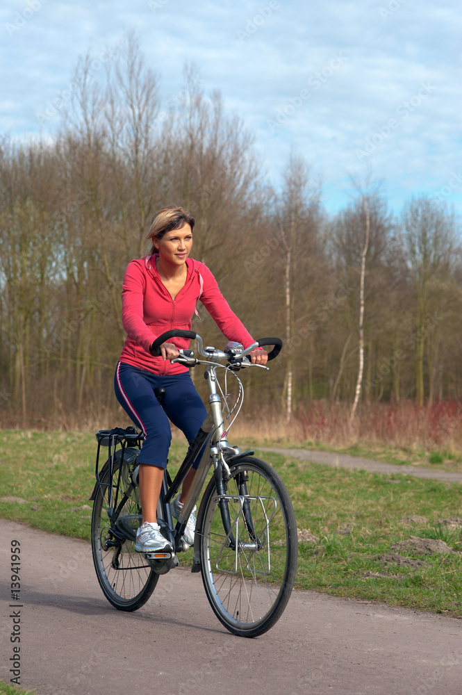 Woman cycling in a park. Woman cycling in a park.