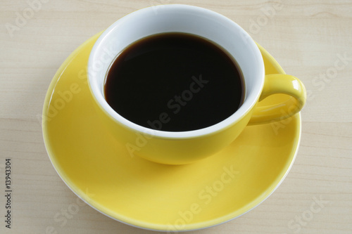 Yellow cup of coffee on wooden table