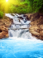 Tuinposter Watervallen Sierlijke waterval over met mos bedekte stenen  © Olga Khoroshunova