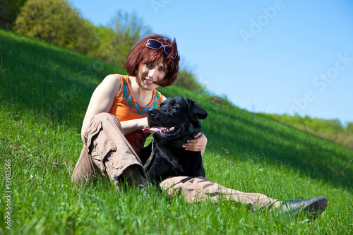 The young woman with black labrador on a green grass © Pumba