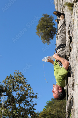 Un grimpeur qui se désaltère sur une paroie rocheuse. photo