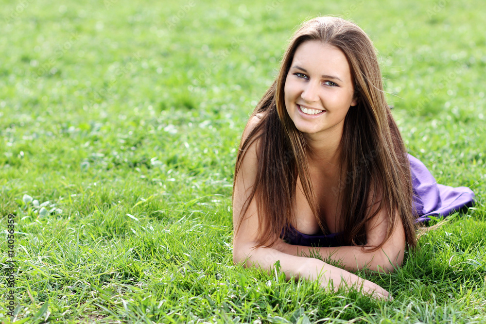 Happy beautiful woman lays on green field Happy beautiful woman lays on green field