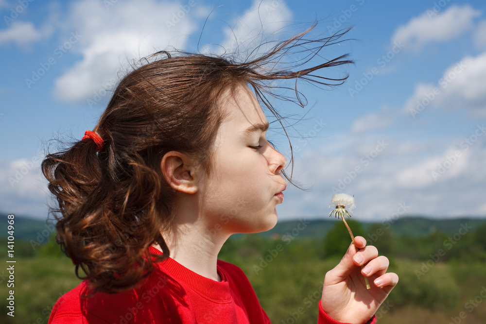 Girl blowing dandelion against blue sky Girl blowing dandelion against blue sky