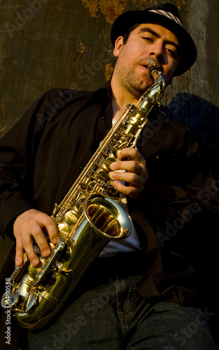 saxophonist plays outdoors against an industrail