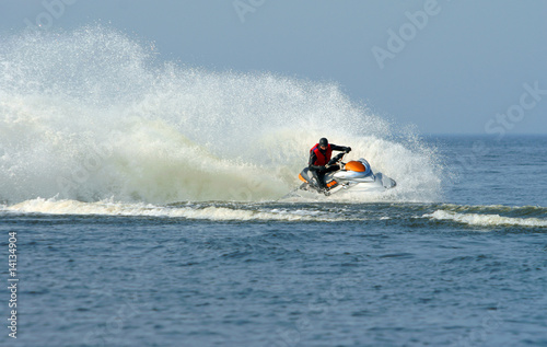 Jet ski in action with water spray on the blue sea
