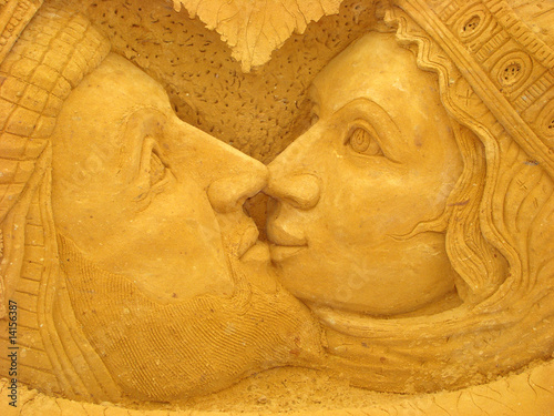 heads of man with a beard and woman in a kiss from sand