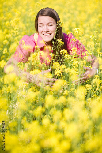 Pretty smiling girl relaxing on green meadow full yellow flowers