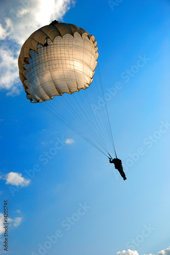 single parachute jumper against blue sky background