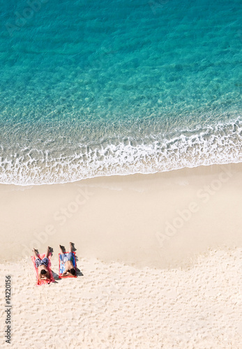 two people lying on tropical beach, lots of copyspace