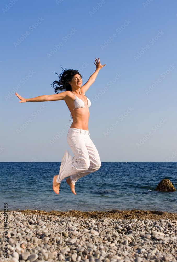 happy young woman jumping in the beach happy young woman jumping in the beach