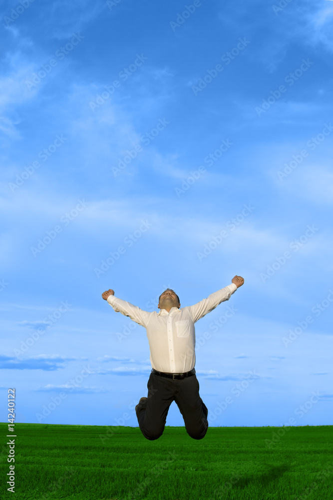 Businessman jumping on the green grass over clouds blue sky Businessman jumping on the green grass over clouds blue sky