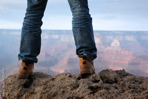 Male feet in hiking boots standing on edge of a cliff