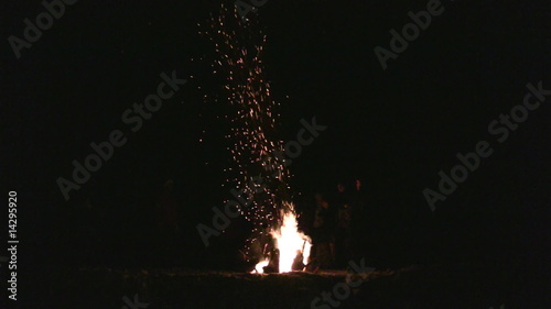 Sparks from fire flying upwards in night photo