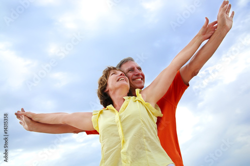 beautiful mature couple standing with arms outstretched
