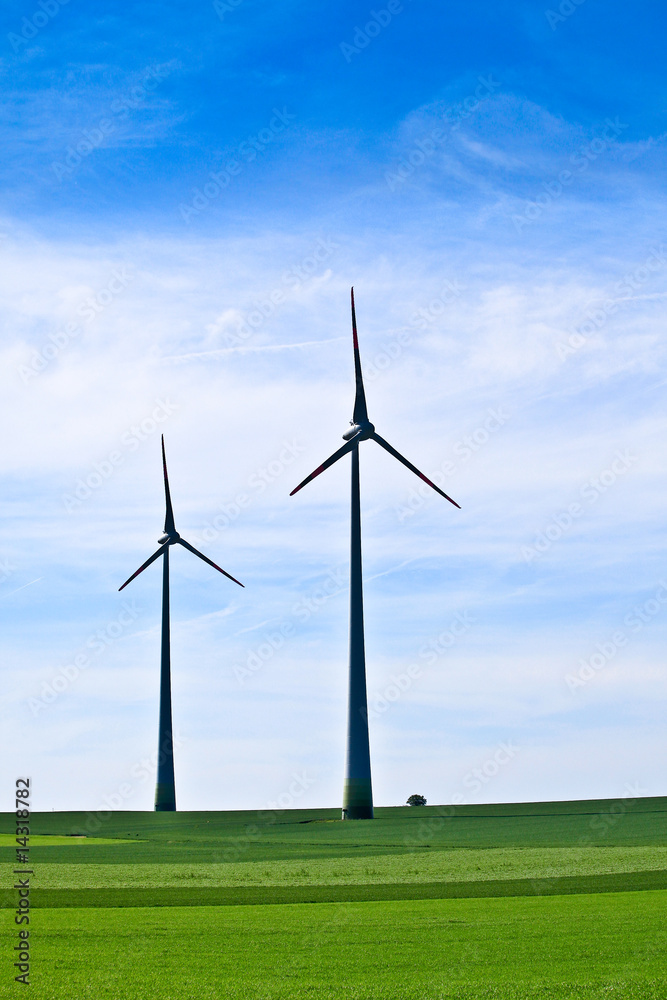 Wind turbines farm in green field over cloudy sky