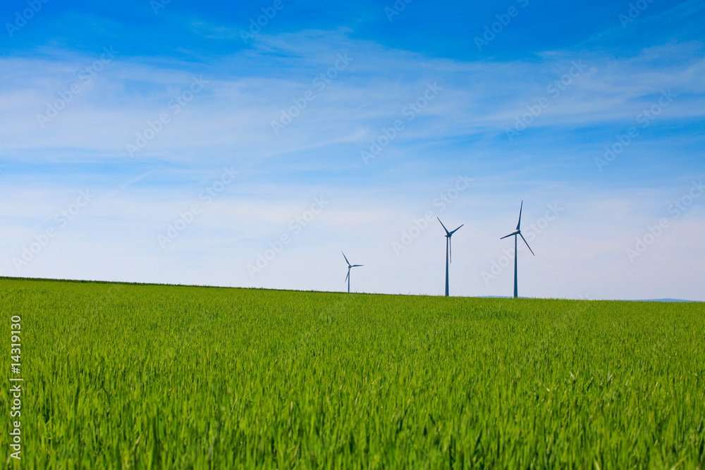 Wind turbines farm in green field over cloudy sky Wind turbines farm in green field over cloudy sky