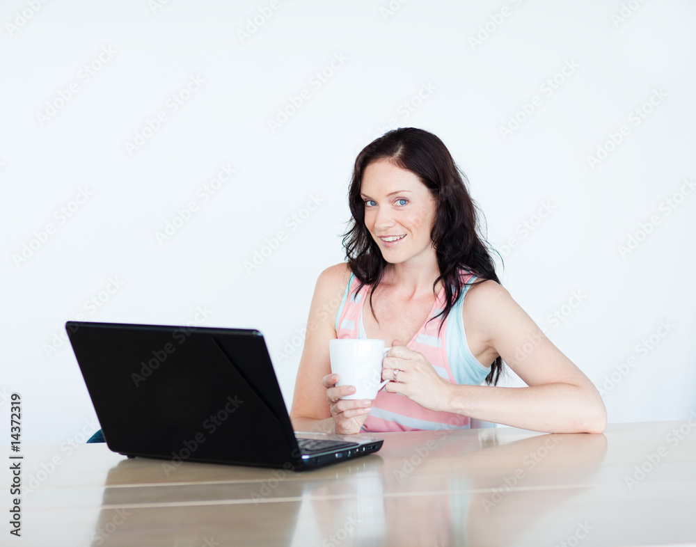 Woman using a laptop and drinking coffee Woman using a laptop and drinking coffee