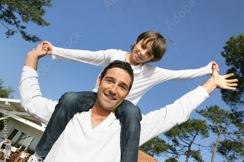 Hombre llevando a su hijo sobre sus hombros en el jardín