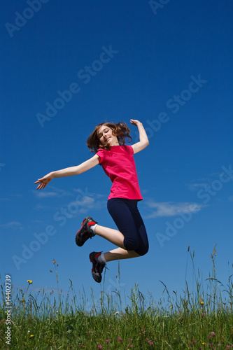 Girl jumping, running against blue sky