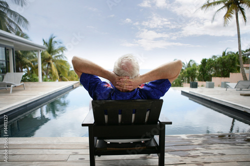 Photographie Homme âgé assis sur une chaise au bord d'une piscine