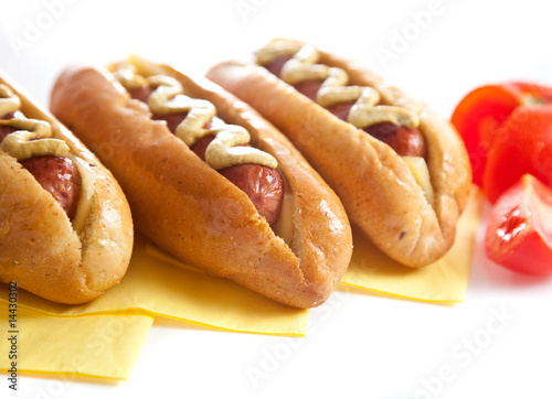 Three hot dogs with tomato on white