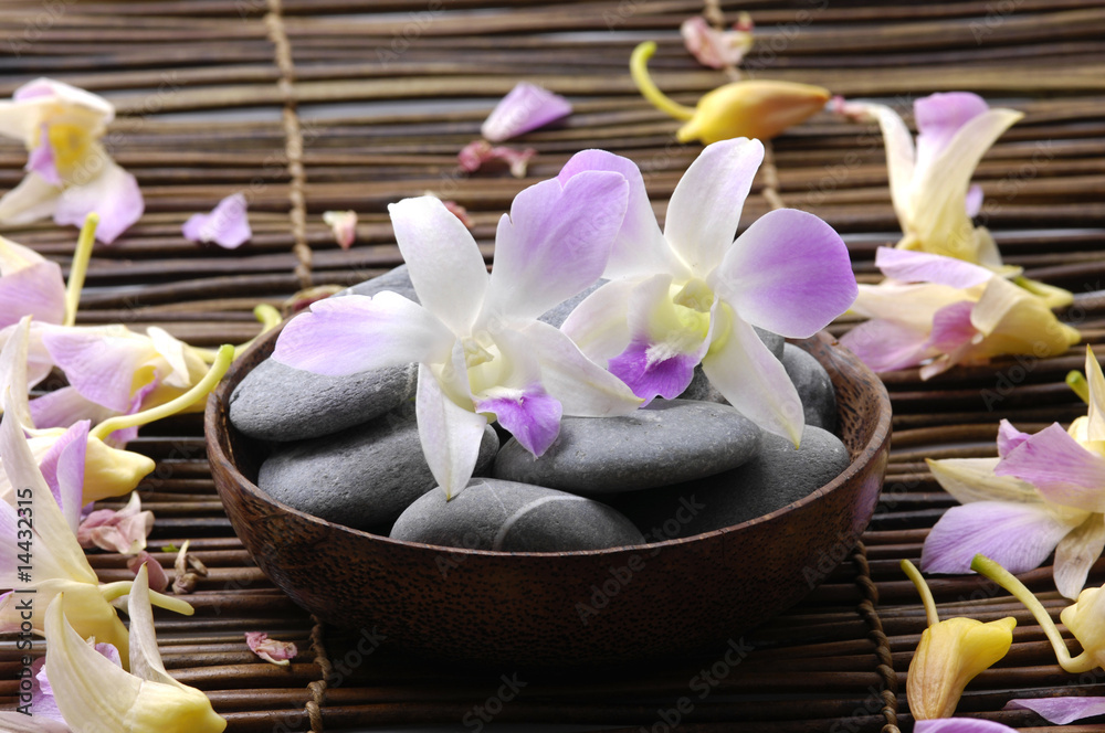 Bowl of orchid with spa stones on petal ,bamboo mat Bowl of orchid with spa stones on petal ,bamboo mat