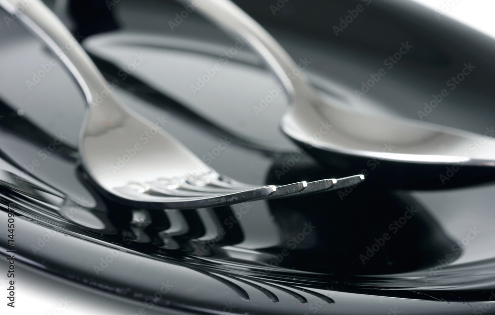Fork and spoon on black plate